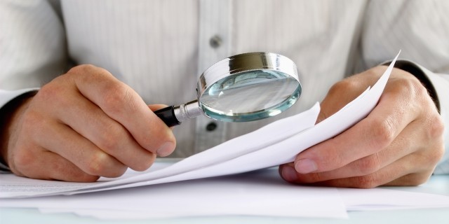 4 Reasons I'm Pursuing a Rare Disease Diagnosis for My Child Businessman looking through a magnifying glass to documents