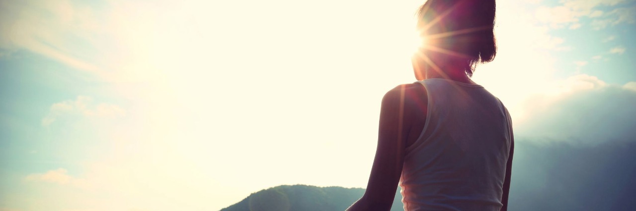 Trying to Heal and Accept Chronic Illnesses That Won't Get Better young yoga woman sit meditation on sunrise mountain peak rock