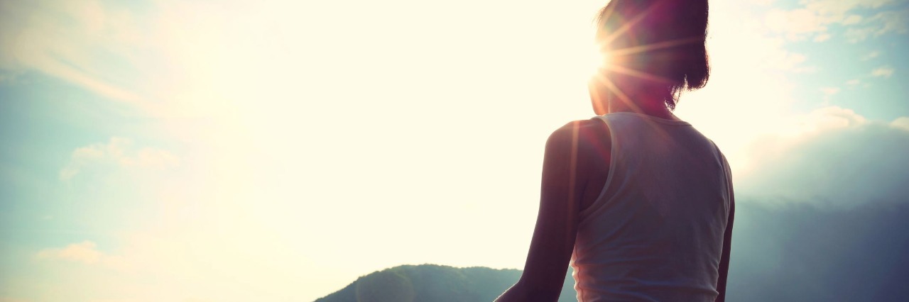 young yoga woman sit meditation on sunrise mountain peak rock