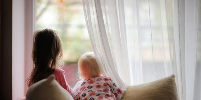 Two little girls in pajamas looking out of the window