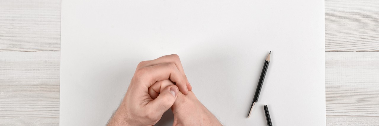 Breaking Depressive Ideology and Thinking About Suicide Closeup masculine folded hands on wooden panel with white paper and broken black pencil in top view. Worry process.