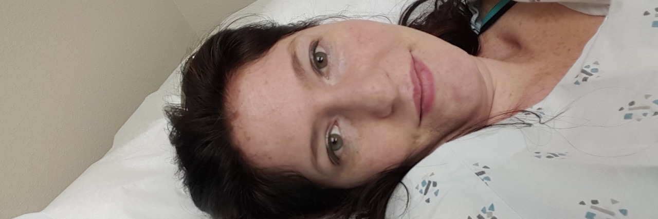 How to Laugh and Smile on Bad Days With Chronic Illness woman lying on bed wearing hospital gown
