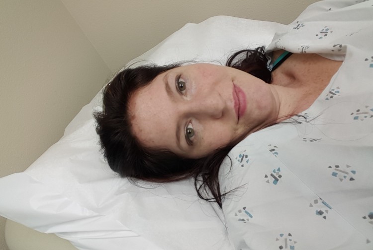 woman lying on bed wearing hospital gown