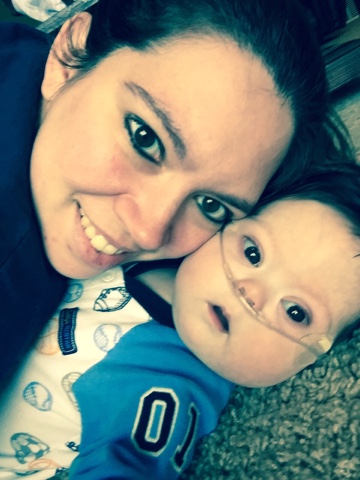 mother smiling with her baby boy wearing an oxygen tube