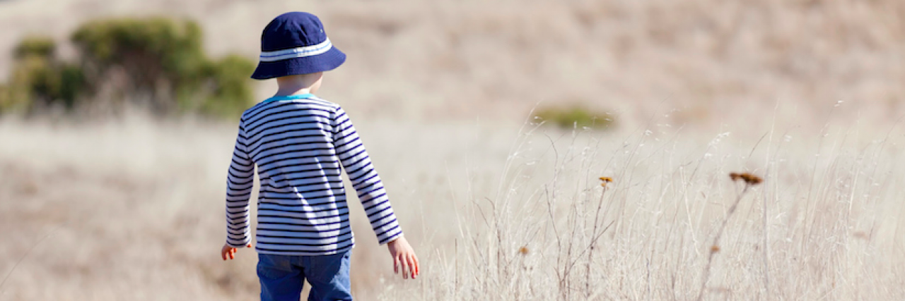 What I've Learned About Supporting My Grandson With Autism boy in hat standing alone in a field of tall yellow grass