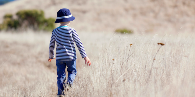 What I've Learned About Supporting My Grandson With Autism boy in hat standing alone in a field of tall yellow grass