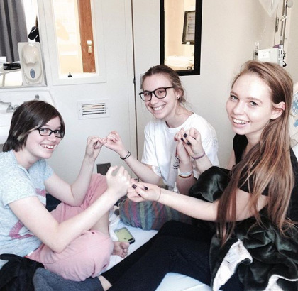 three teenage girls linking fingers sitting in hospital