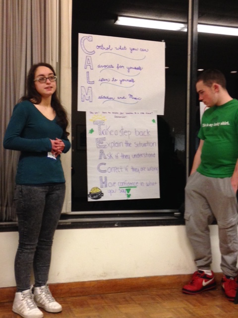 two teenagers standing and talking about a poem written on a poster