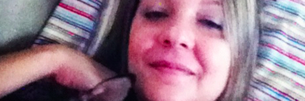 When I Mourn Who I Wanted to Be Before Chronic Illness Woman lying on striped pillow with small dog