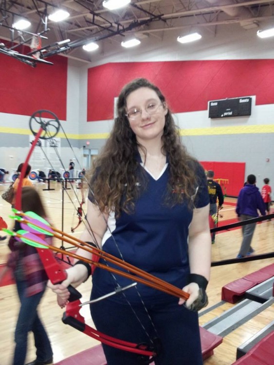 woman holding bow and arrow for archery inside gym