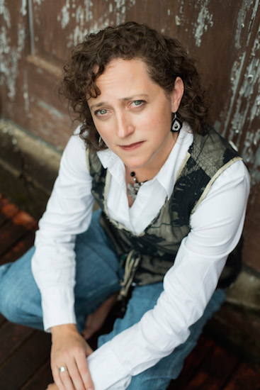 a woman in a vest and white shirt looking up at the camera