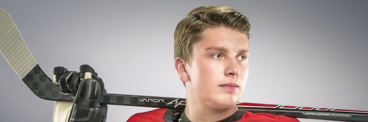 Contributor, a young man, wearing ice hockey gear and holding a hockey stick