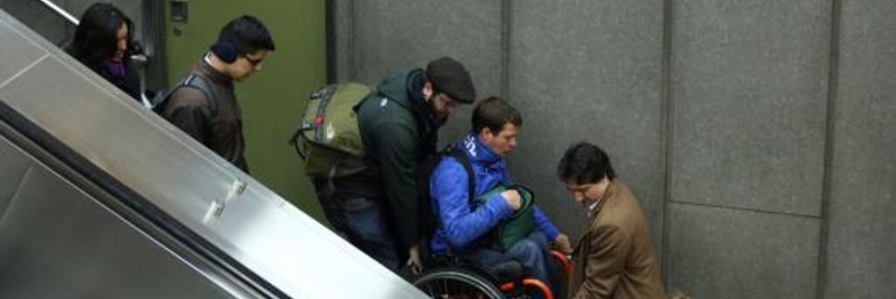 Justin Trudeau helps a man in a wheelchair down a flight of stairs.