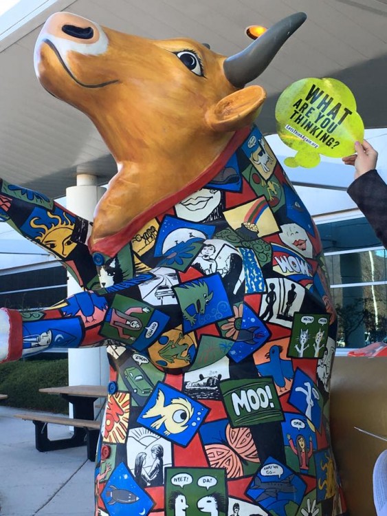 A volunteer holds up a 'What Are You Thinking?' thought bubble next to a decorative statue of a pig in Pennsylvania.