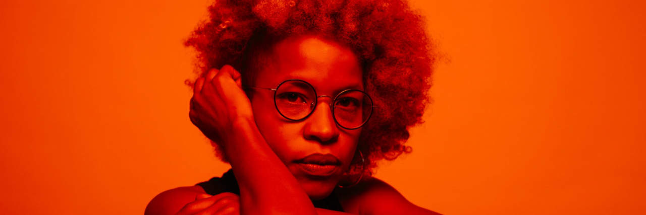 woman with an afro and glasses covered in red light