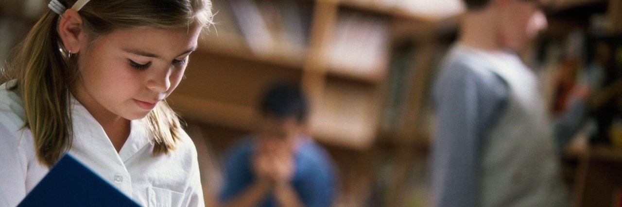 Mother Writes Letter to Classmates of Daughter Who Is Hard of Hearing young girl reading book in school library