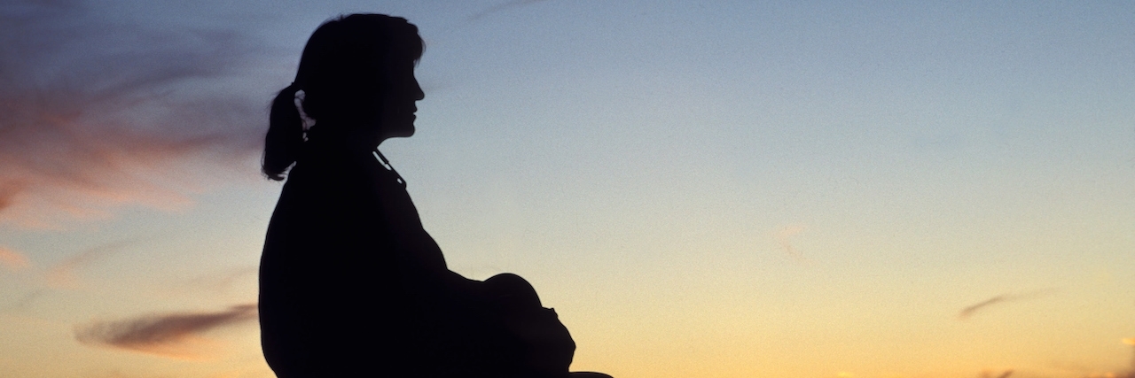 silhouette of woman looking at sunset