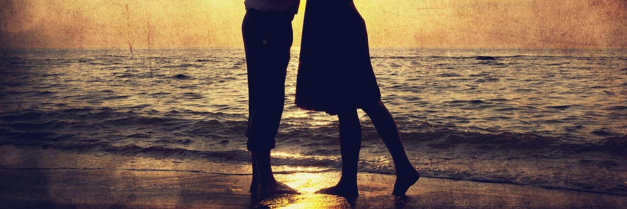 Dating Someone With OCD and Anxiety Couple kissing under umbrella at the beach in sunset. Photo in old image style.