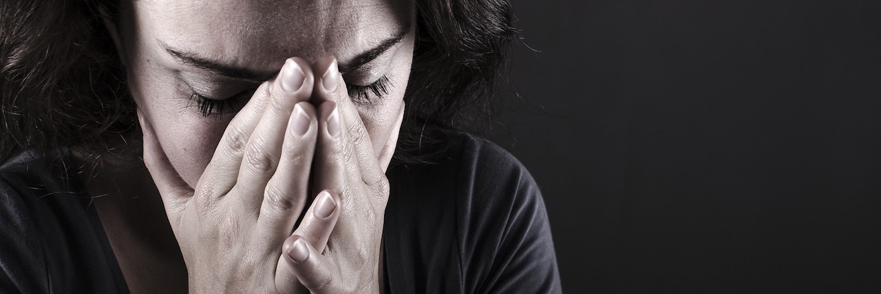 Depressed woman with hands over her face.