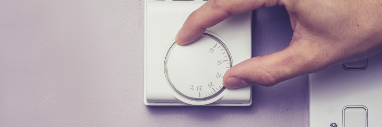 How the Office Air Conditioner Affects My Migraines Hand turning dial on thermostat
