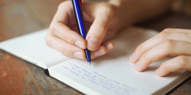 hands writing a letter