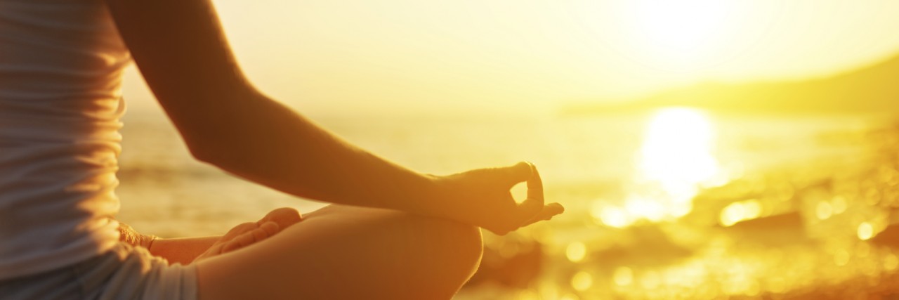 hand of woman meditating in a yoga pose on beach