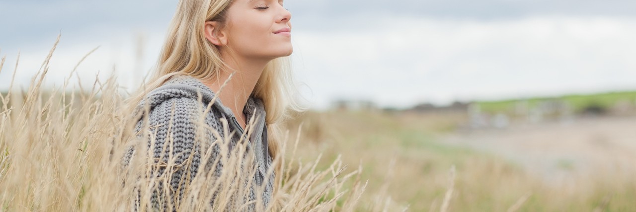 woman sitting in grass by beach