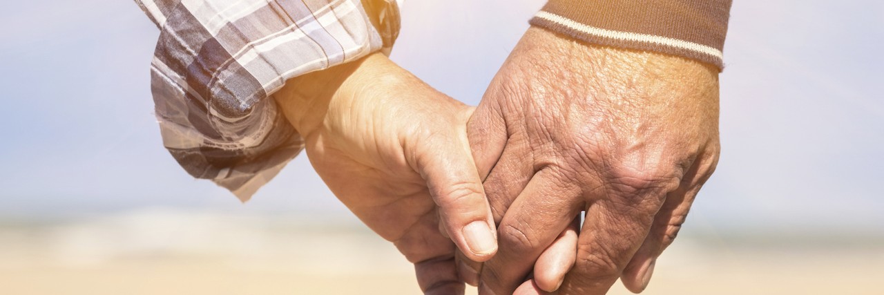 Senior couple in love walking at the beach holding hands