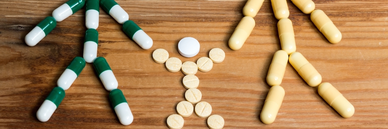 Taking Medications With an ADHD and Autism Diagnosis Family of three made from pills on a wooden background.