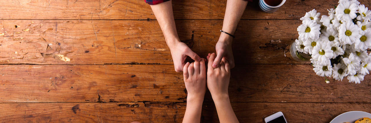 Love Letter to Husband, From Wife With Bipolar Disorder Two hands holding on a coffee table.