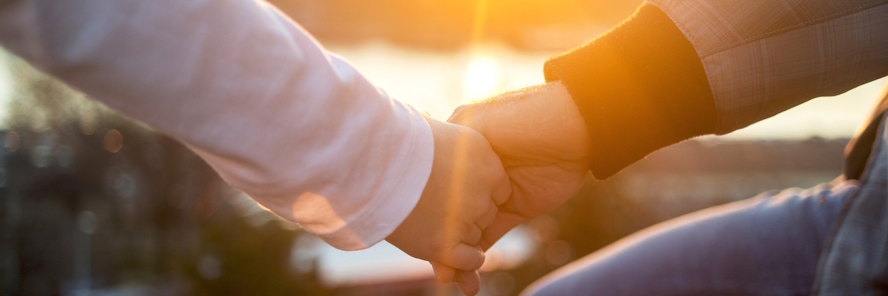 How to Support a Friend With Health Challenges Unrecognizable romantic couple holding hands at sunset.