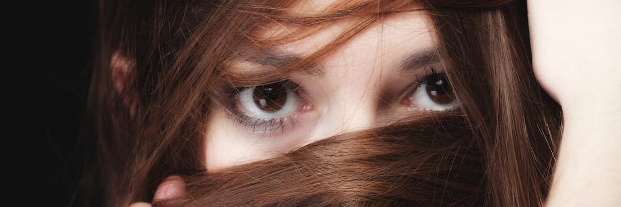 woman covers the face by long brown hairs