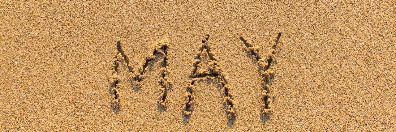 Surviving May, Mental Health Month May - word drawn on the sand beach with the soft wave.