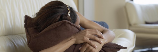 Woman sleeping on sofa with arm around pillow