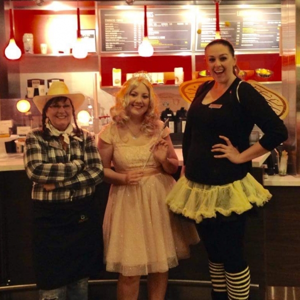 three women wearing Halloween costumes at a restaurant