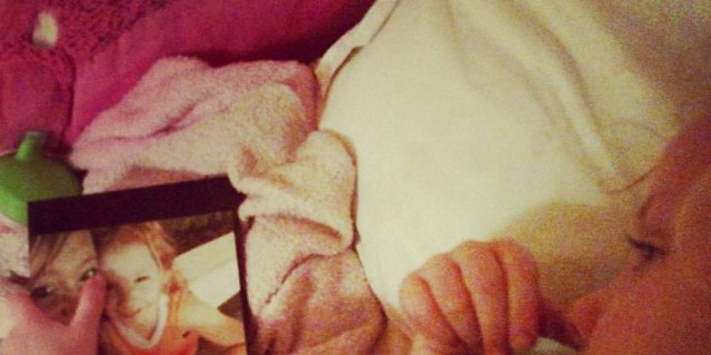 A Child Doesn't Need Words to Say 'I Love You' young girl lying in bed looking at frame photo of her with her mother