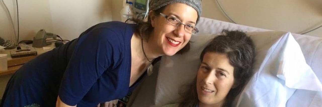 woman lying in hospital bed with her sister standing next to her