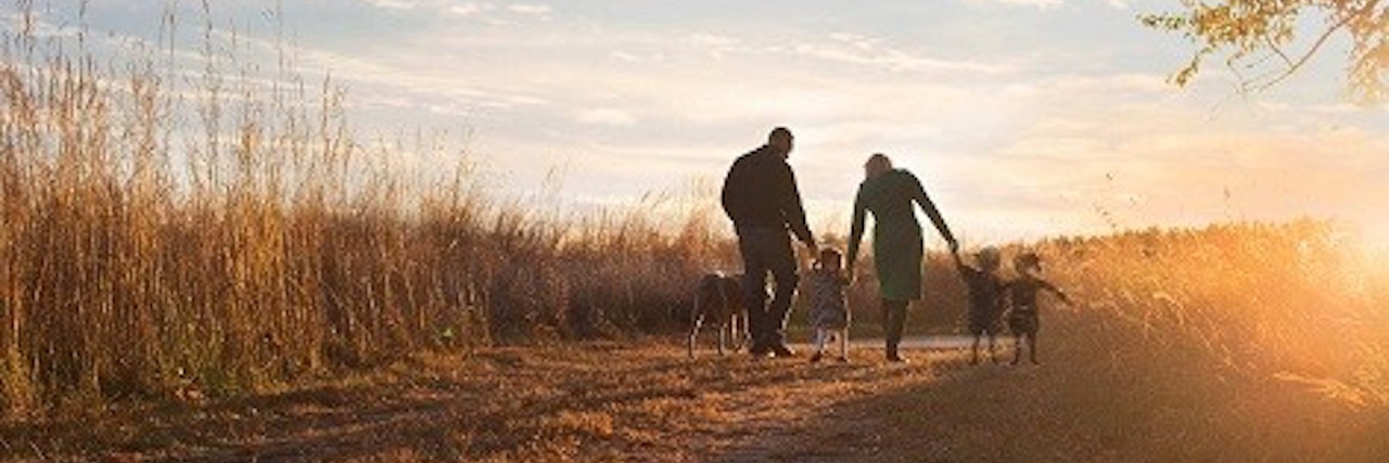 family walking down unpaved road by field