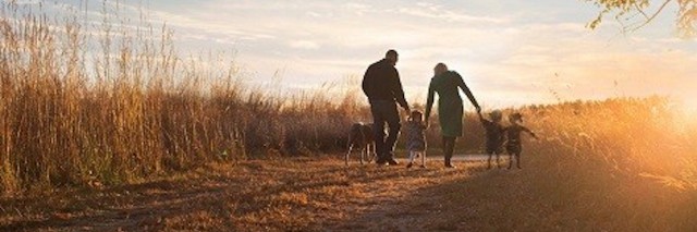 family walking down unpaved road by field