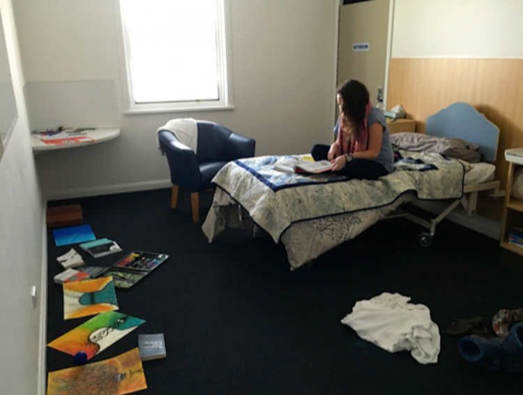 a woman sitting on her bed at a psychiatric hospital