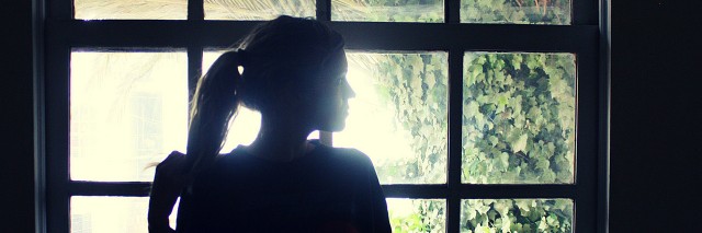 Lonely woman standing by window.