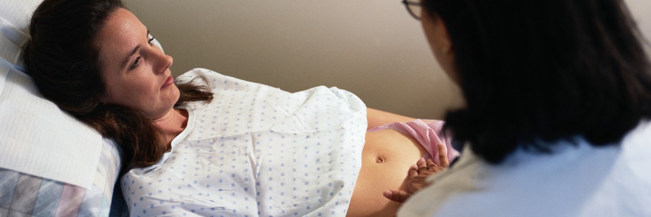 OBGYN touches stomach of pregnant woman