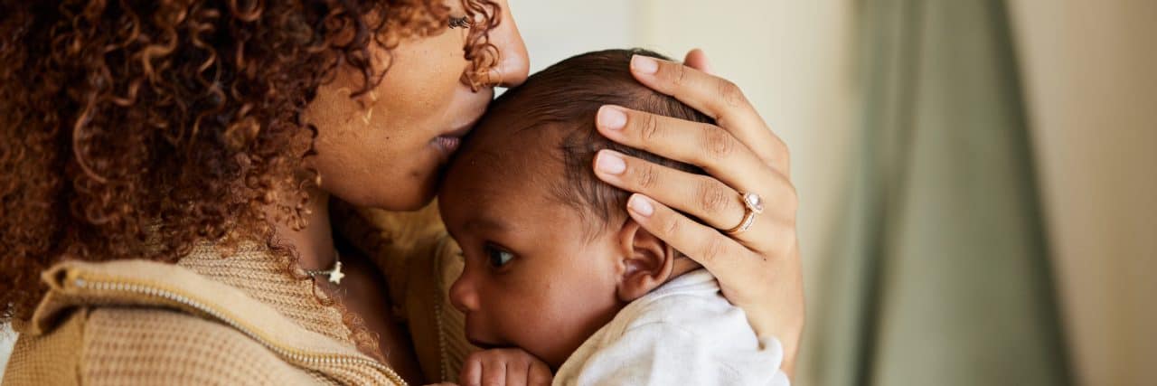 Raising a Child With Mast Cell Activation Syndrome Mom kissing baby on head.