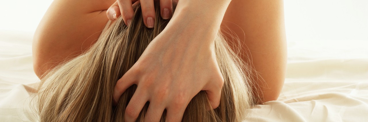 When Trichotillomania is a Part of Your Everyday Life Rear view image of woman with blonde hair runs her fingers through her hair