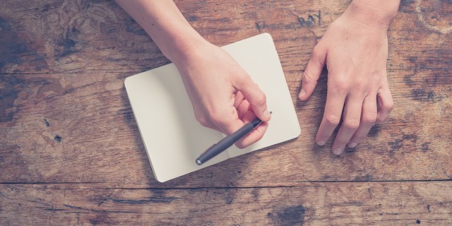 Woman writing in notepad at wooden table