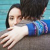 Woman looking at camera while embracing man who faces opposite direction