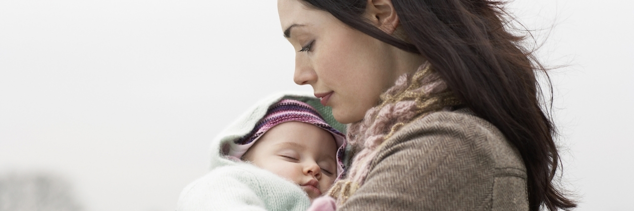 Misconceptions About Postpartum Psychosis Mother carring sleeping baby in park