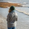girl in knit hat and sweater, walking on the coast