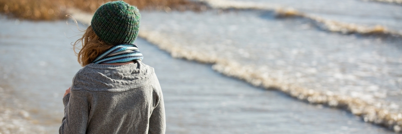 girl in knit hat and sweater, walking on the coast