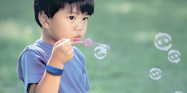 A young boy is shown blowing bubbles while wearing a Reveal band in a photo provided by Awake Labs.